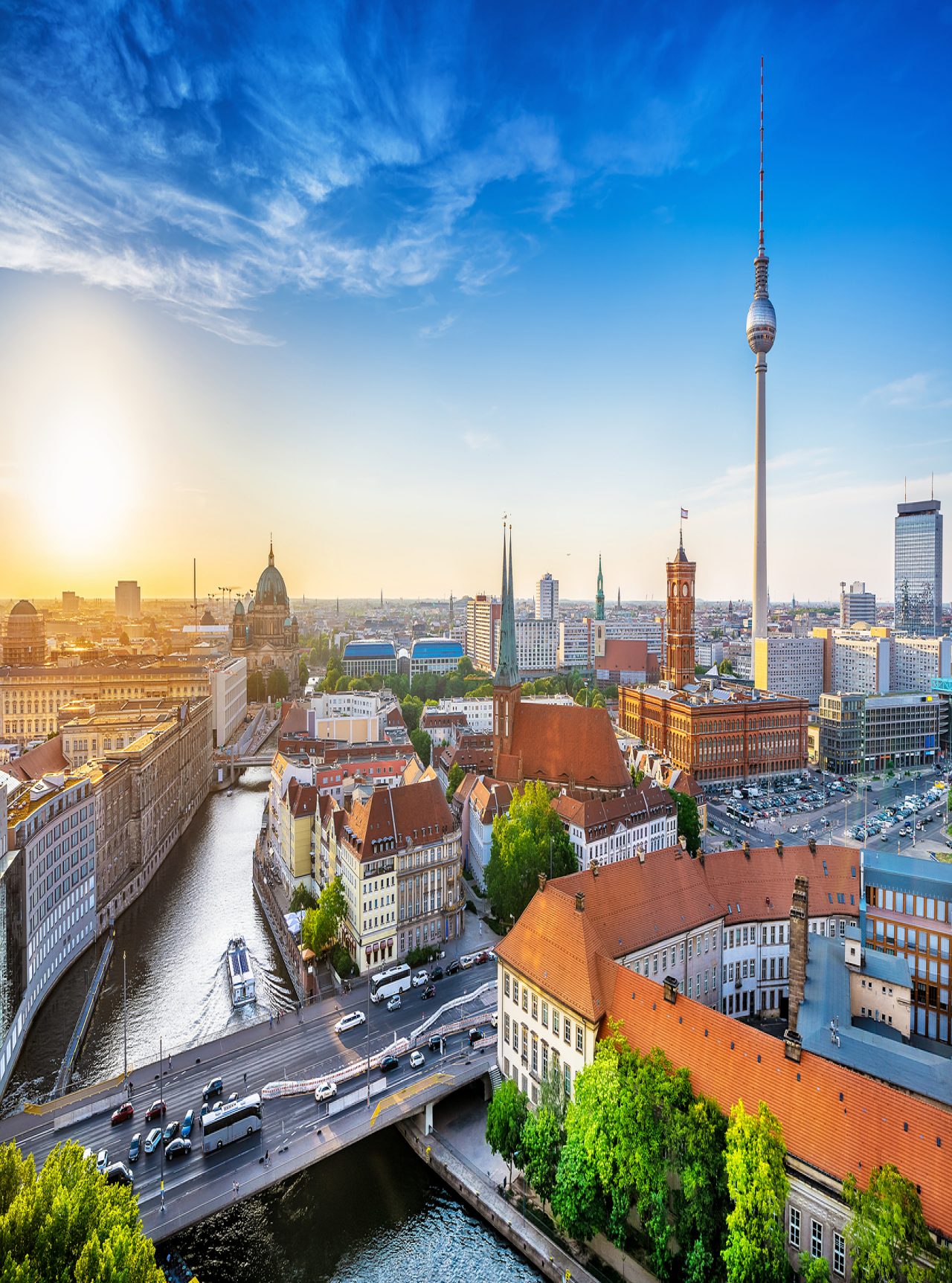 Aerial view over the city of Berlin, with a bridge with cars passing, several buildings, and the iconic television tower