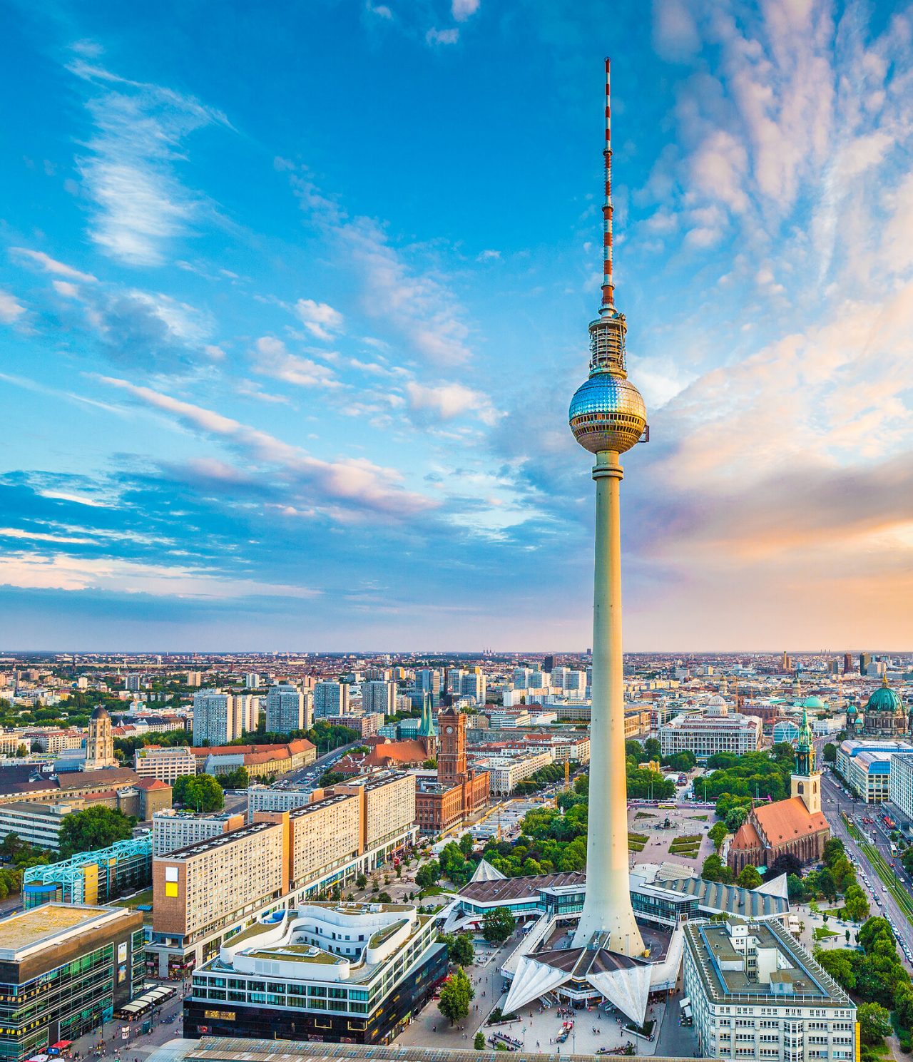 Famous Television Tower located in Alexanderplatz, surrounded by the city of Berlin, with sunset in the background
