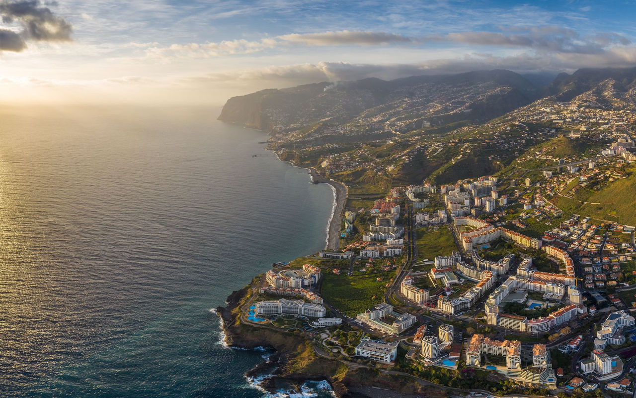 Aerial view of the city of Funchal in Madeira, with a dense urban areas, and mountains in the background