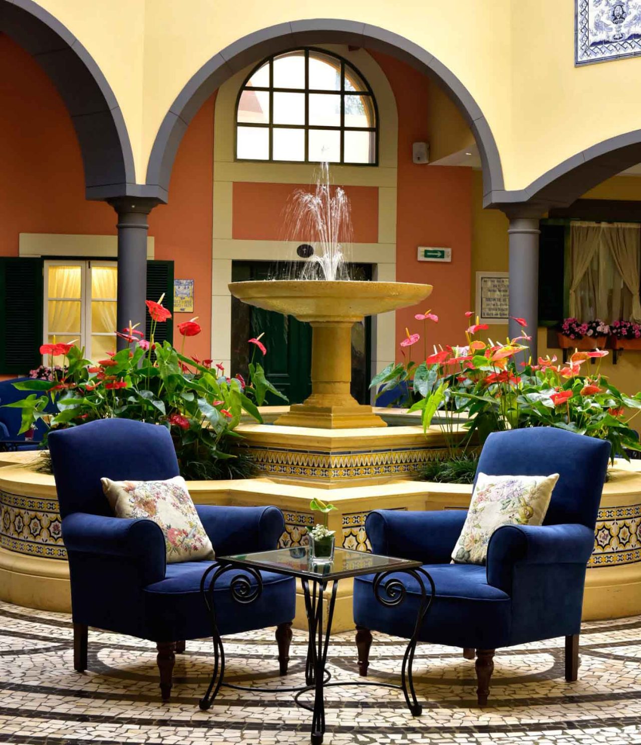 The bar A Fonte, at the Hotel de Charme in Madeira has a fountain with water and flowers and two blue armchairs