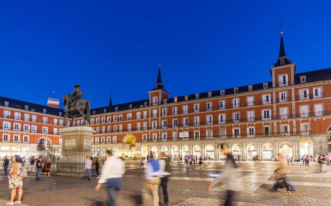 Plaza Mayor, in the historic center of Madrid, at night, with many tourists waljing around the Pestana Plaza Mayor is located