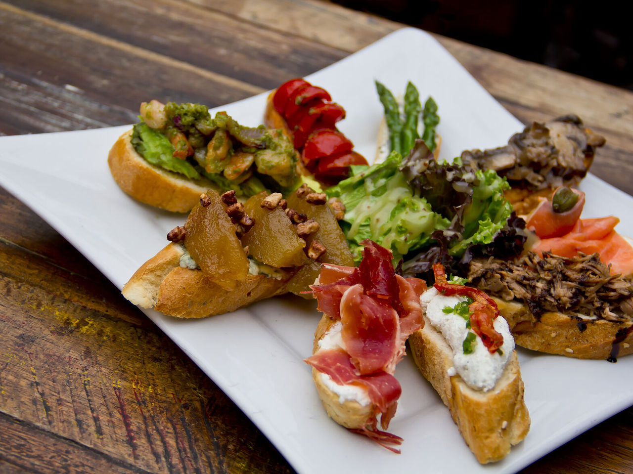  Dish with bocadillos, typical Spanish tapas, with various toppings on bread, from ham to cheese and tomato