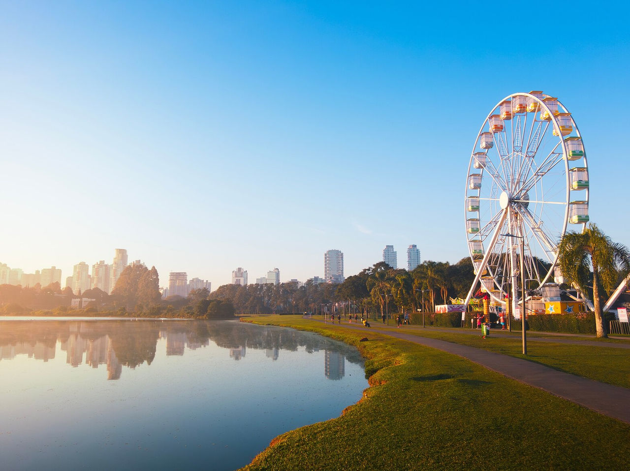 Picturesque view with Curitiba Ferris wheel, lake, and city in the background on a sunny day