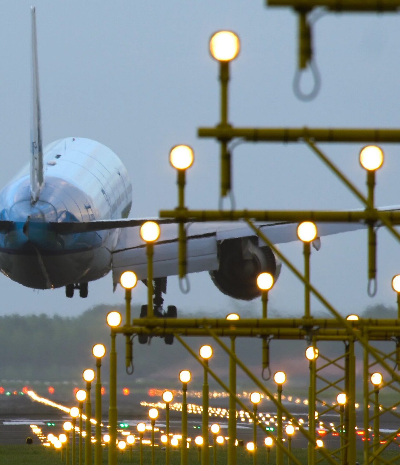 View of a plane landing on the runway at Rio de Janeiro airport, with several lights illuminating the way